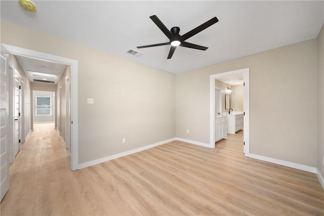 unfurnished bedroom featuring baseboards, visible vents, light wood finished floors, ceiling fan, and connected bathroom