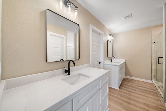 bathroom featuring visible vents, a shower stall, wood finished floors, and a sink