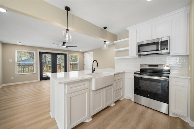 kitchen featuring light countertops, appliances with stainless steel finishes, french doors, a peninsula, and a sink