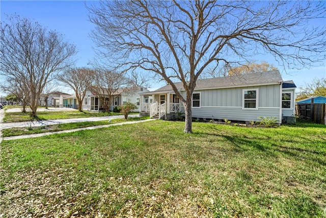 view of front of property with board and batten siding, a front yard, and fence