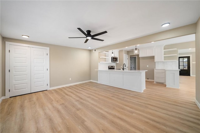 unfurnished living room featuring a sink, baseboards, light wood-style floors, and a ceiling fan