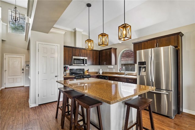 7217 Dunns Point Dr, Corpus Christi, TX 78414 - kitchen featuring appliances with stainless steel finishes, dark brown cabinetry, high vaulted ceiling, a center island, and light stone counters