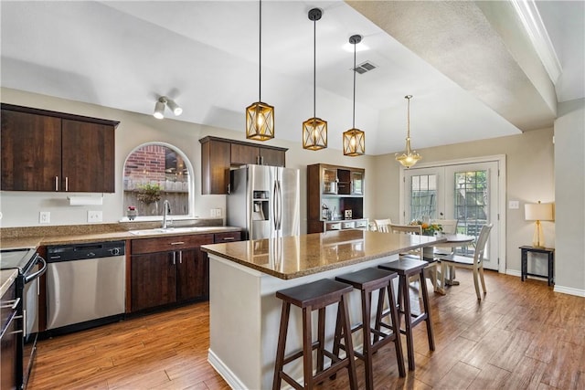 7217 Dunns Point Dr, Corpus Christi, TX 78414 - kitchen featuring appliances with stainless steel finishes, dark brown cabinetry, a breakfast bar, light wood-style flooring, and a center island