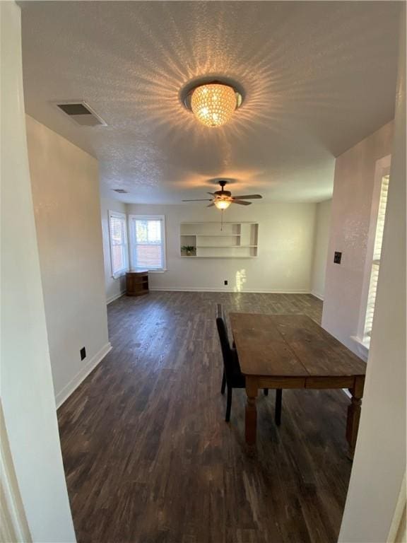 unfurnished dining area featuring ceiling fan, dark wood-type flooring, and a textured ceiling