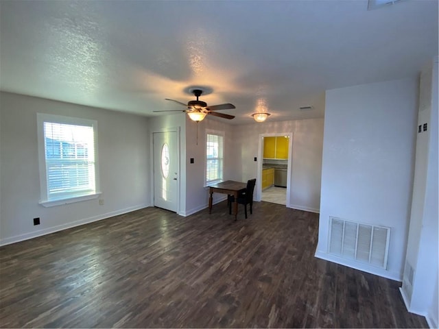 unfurnished living room with a textured ceiling, a wealth of natural light, ceiling fan, and dark hardwood / wood-style floors