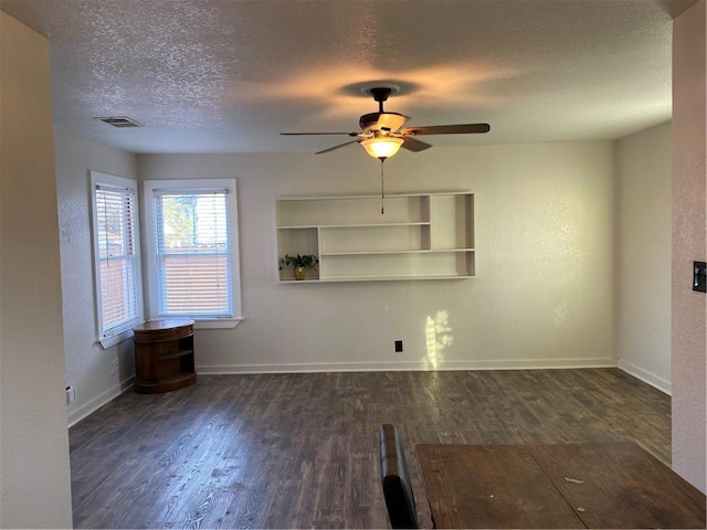 empty room with ceiling fan, dark hardwood / wood-style flooring, and a textured ceiling