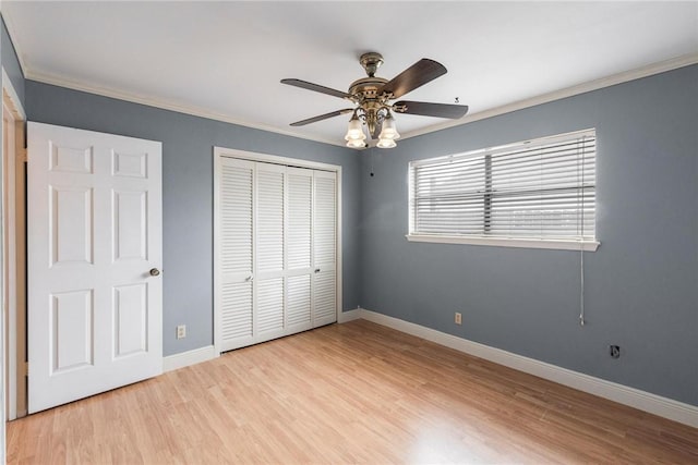 unfurnished bedroom with light wood finished floors, a closet, ornamental molding, ceiling fan, and baseboards