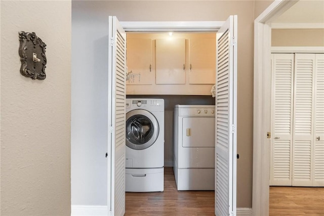 laundry room featuring wood finished floors, laundry area, and separate washer and dryer