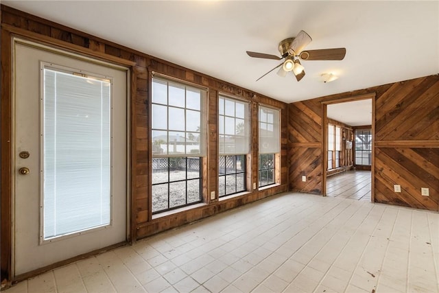 unfurnished room featuring ceiling fan and wood walls