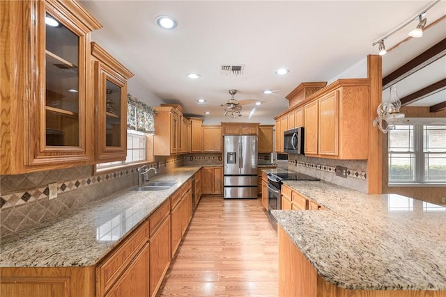 kitchen featuring light stone counters, visible vents, stainless steel appliances, and a sink