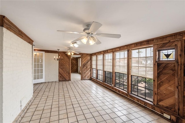 unfurnished sunroom featuring ceiling fan with notable chandelier