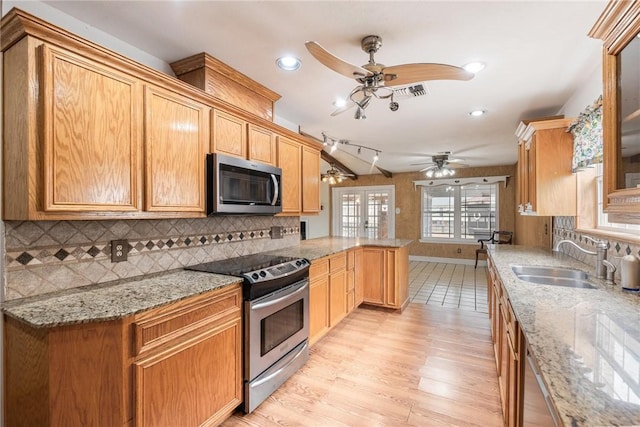 kitchen featuring a peninsula, tasteful backsplash, appliances with stainless steel finishes, and a sink