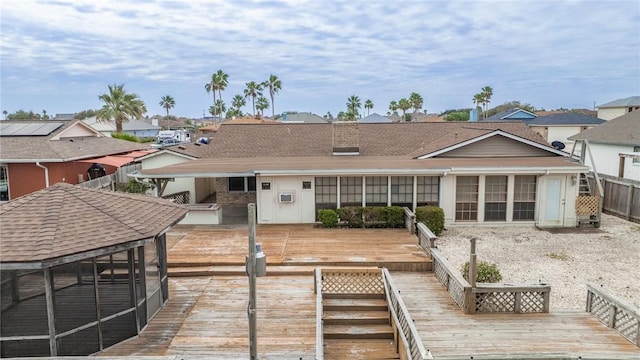 back of house featuring roof with shingles and a wooden deck