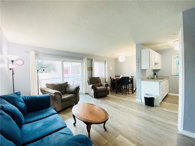 living room with light hardwood / wood-style floors, a textured ceiling, and sink