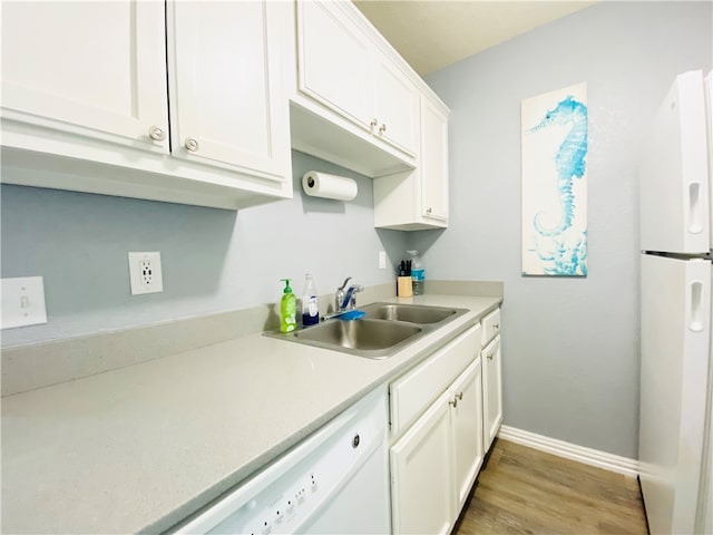 kitchen with white appliances, white cabinetry, sink, and hardwood / wood-style flooring