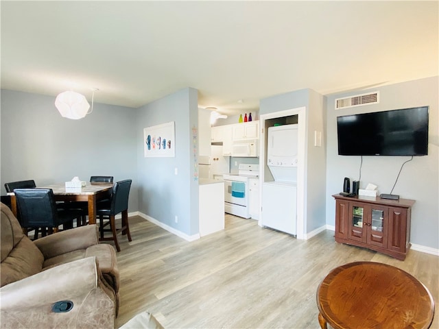 living room featuring light wood-type flooring and stacked washer / dryer