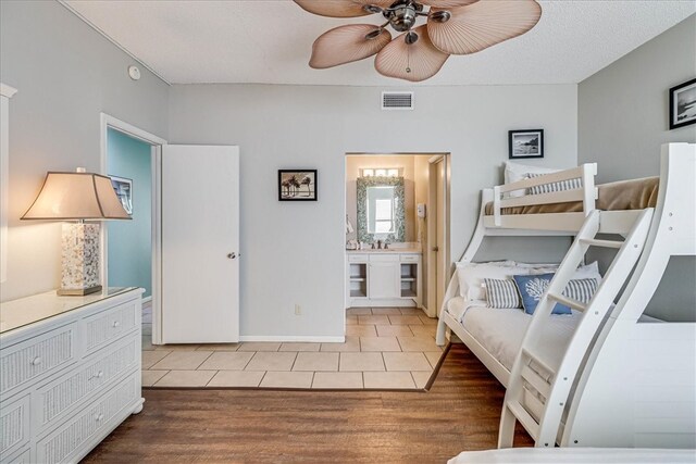 bedroom featuring ensuite bathroom, a textured ceiling, hardwood / wood-style flooring, and ceiling fan