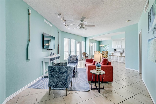 living room with a textured ceiling, light tile patterned floors, and ceiling fan