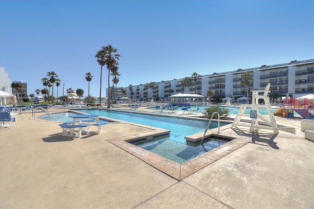 view of swimming pool featuring a hot tub and a patio