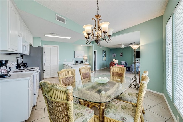 tiled dining area featuring sink, a textured ceiling, and ceiling fan with notable chandelier