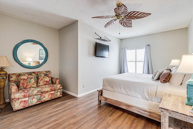 bedroom with a textured ceiling, hardwood / wood-style floors, and ceiling fan