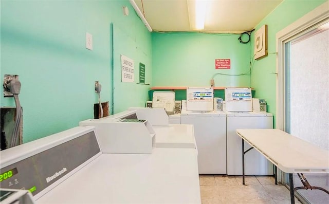 clothes washing area with washing machine and dryer and light tile patterned floors