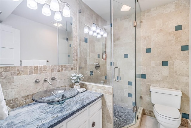 bathroom with walk in shower, tile patterned flooring, toilet, vanity, and tile walls