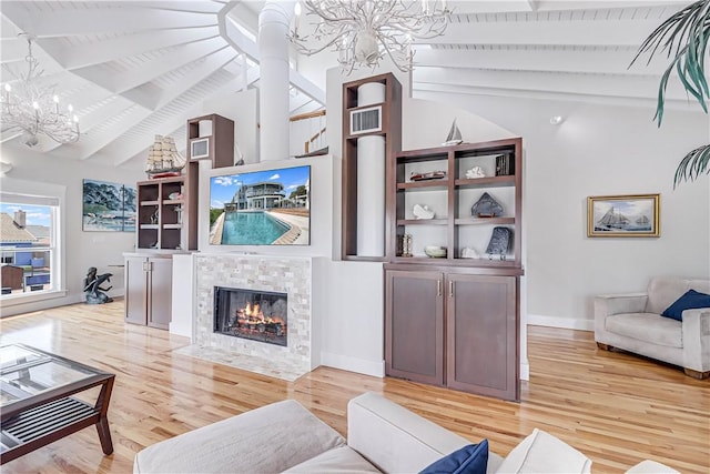 living room featuring a tile fireplace, a chandelier, beamed ceiling, and light hardwood / wood-style floors