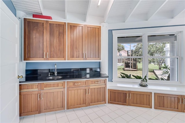 kitchen featuring sink, beamed ceiling, and light tile patterned floors