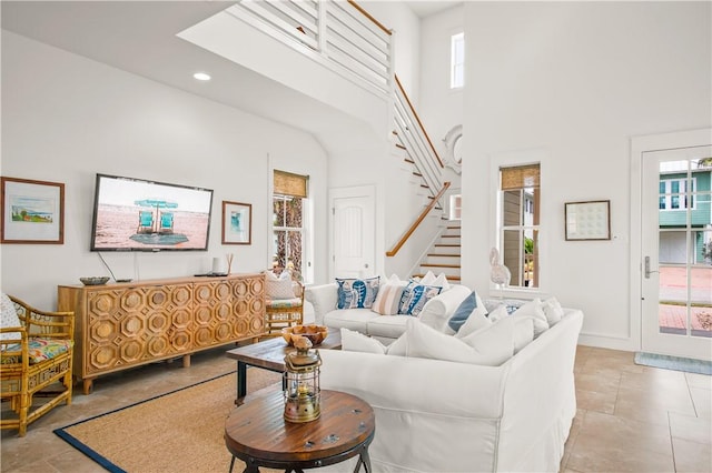 living room featuring a wealth of natural light, recessed lighting, stairs, and a towering ceiling