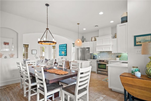 dining area featuring arched walkways, a notable chandelier, recessed lighting, and baseboards