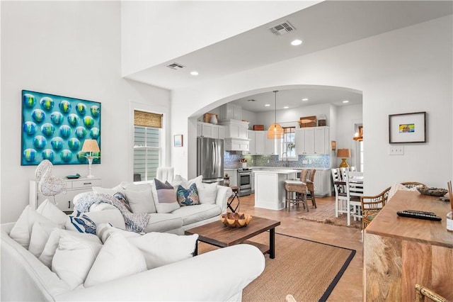 living room with recessed lighting, arched walkways, and visible vents