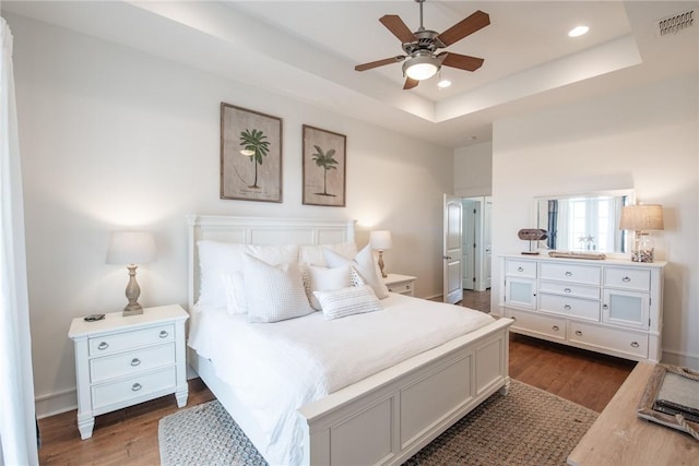 bedroom featuring a tray ceiling, dark wood-type flooring, and visible vents