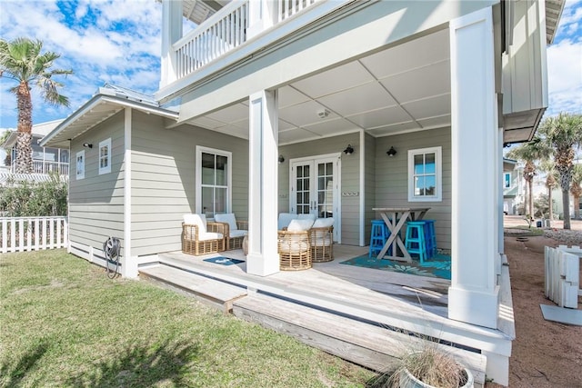 exterior space with french doors, a balcony, a lawn, and fence