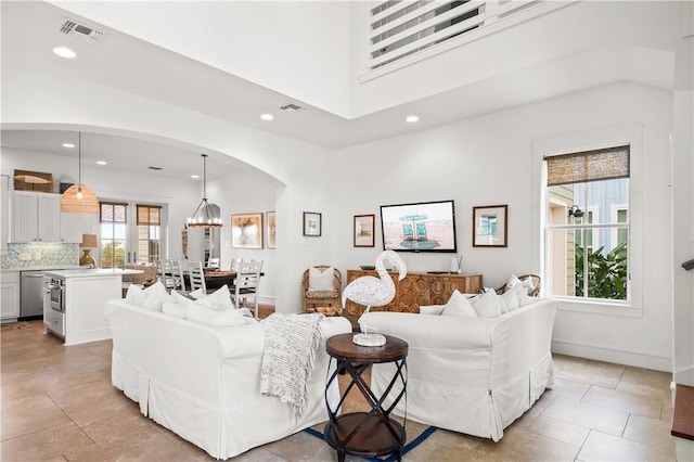 living area with visible vents, recessed lighting, a high ceiling, an inviting chandelier, and arched walkways