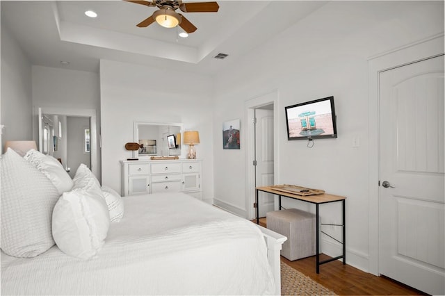 bedroom featuring visible vents, a ceiling fan, a tray ceiling, dark wood finished floors, and recessed lighting