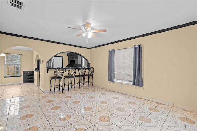 empty room featuring light tile patterned floors, visible vents, a ceiling fan, and ornamental molding