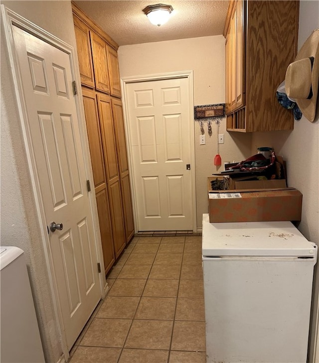 washroom with cabinets, light tile patterned flooring, a textured ceiling, and washing machine and dryer