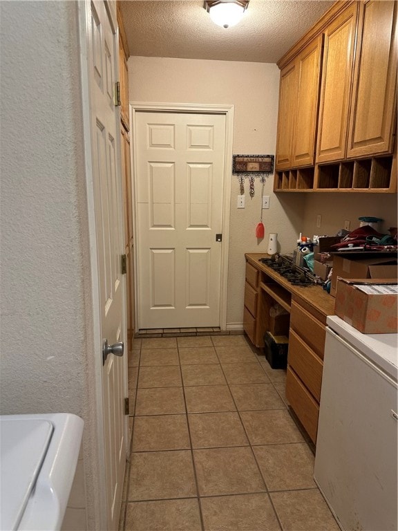 interior space featuring fridge, a textured ceiling, and light tile patterned floors