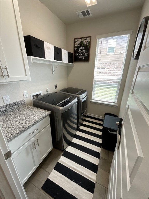 washroom with dark tile patterned flooring, cabinets, and separate washer and dryer