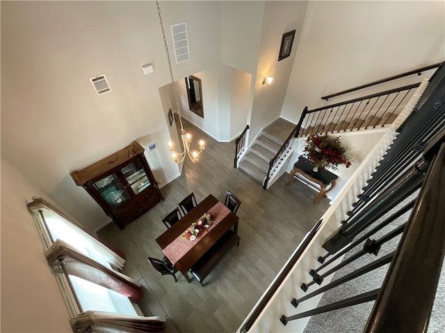 living room with a towering ceiling, wood-type flooring, and a notable chandelier