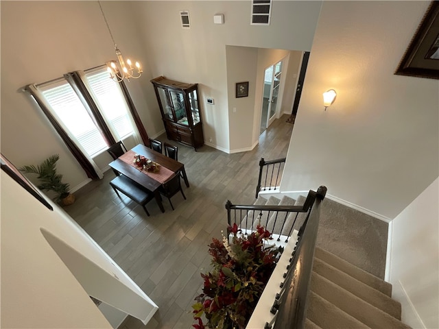 stairway featuring a towering ceiling, hardwood / wood-style flooring, and an inviting chandelier