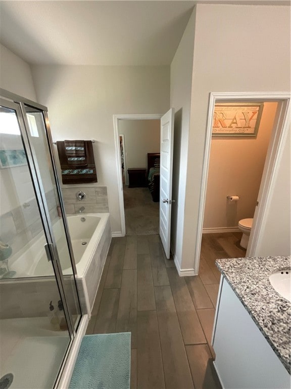 full bathroom with hardwood / wood-style floors, independent shower and bath, vanity, and toilet