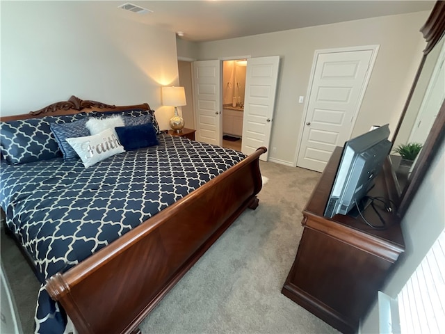 bedroom with connected bathroom and light colored carpet