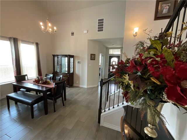 dining room featuring dark wood-type flooring, a chandelier, and a high ceiling