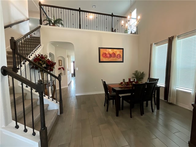 dining space with a chandelier, hardwood / wood-style flooring, and a high ceiling