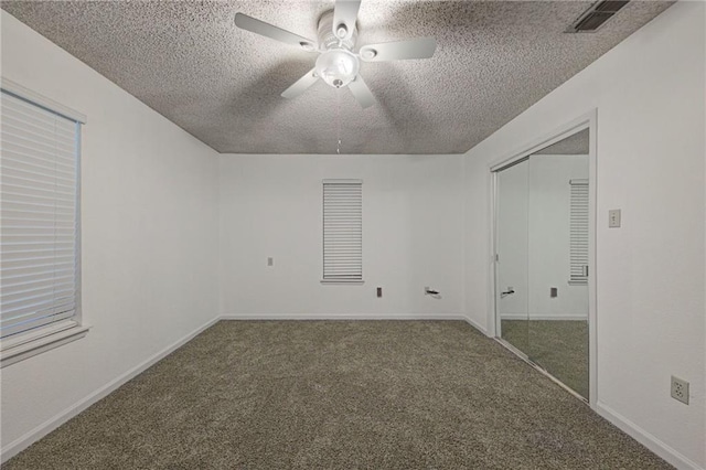 unfurnished bedroom featuring ceiling fan, a closet, a textured ceiling, and dark colored carpet