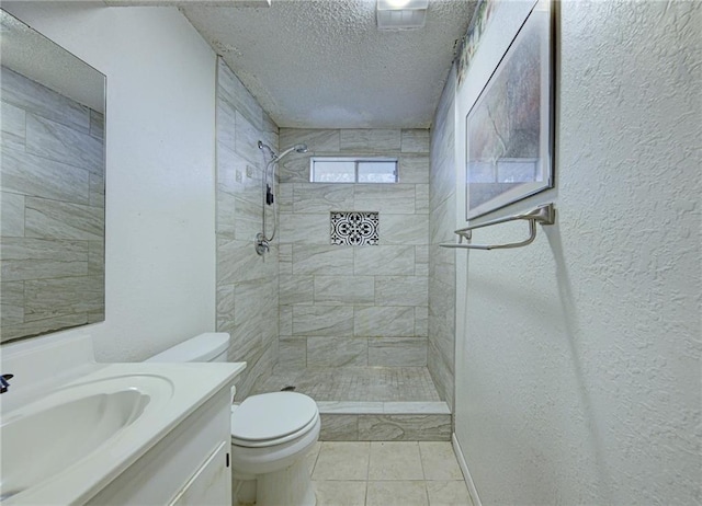 bathroom with tiled shower, vanity, a textured ceiling, and toilet