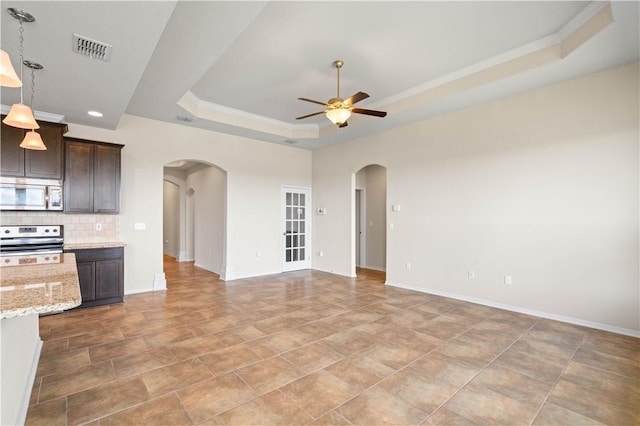 1733 Rhumba Trl, Corpus Christi, TX 78410 - unfurnished living room with arched walkways, a raised ceiling, ceiling fan, ornamental molding, and baseboards