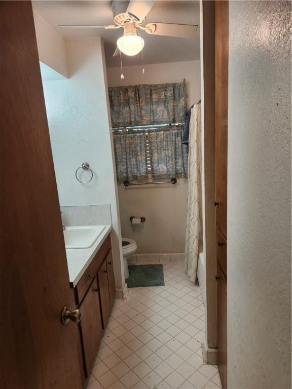 full bathroom with vanity, shower / tub combo with curtain, ceiling fan, tile patterned flooring, and toilet